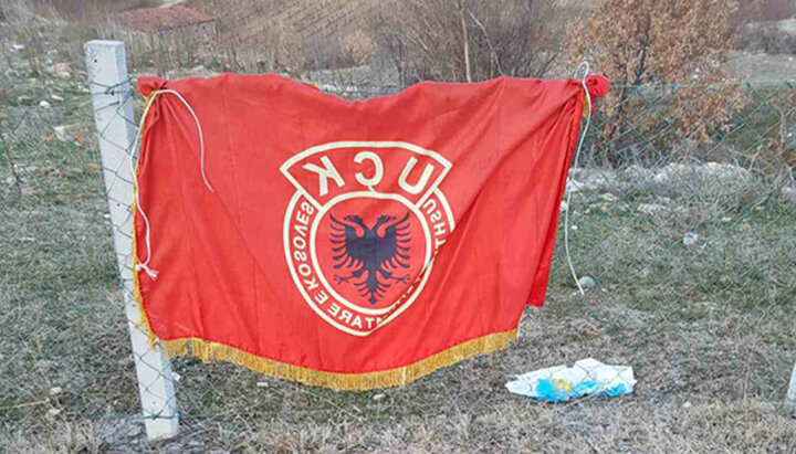 Флаг албанской военизированной организации АОК на заборе под церковью Святого Иоанна Крестителя, Велика-Хоча, Сербия. Фото: kim.gov.rs