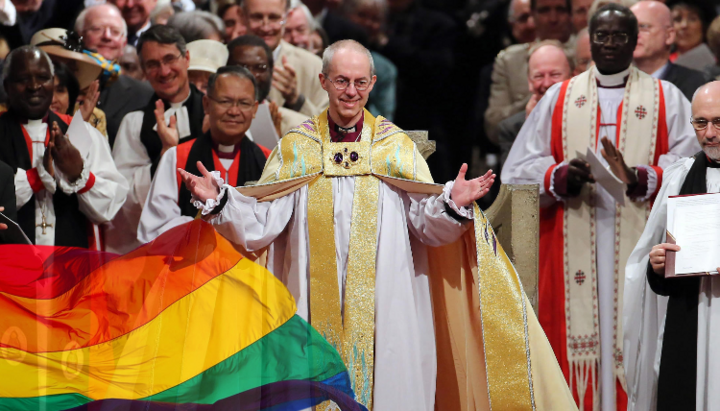 Архиепископ Кентерберийский Джастин Уэлби на фоне ЛГБТ-флага. Фото: point.md