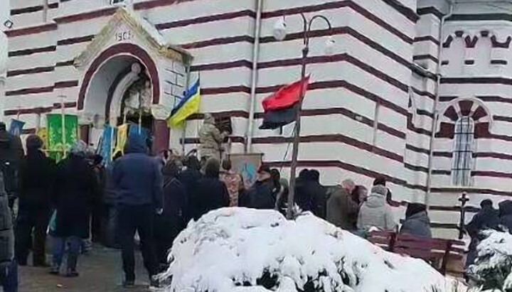 Επιδρομείς κόβουν την ταμπέλα από τον τοίχο του ναού στη Zadubrovka. Φωτογραφία: στιγμιότυπο οθόνης του βίντεο στο Telegram κανάλι της επισκοπής Τσερνιβτσί και Μπουκοβίνα της UOC