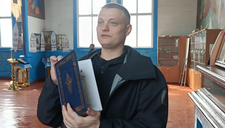 An OCU activist in Trebukhiv with a Bible, which he promised to 
