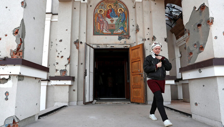 Женщина выходит из Свято-Троицкой церкви во время православного пасхального богослужения в Мариуполе, Украина, 24 апреля 2022 года. Фото: nationalreview.com