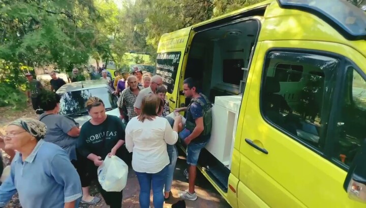 Представники Соціального відділу УПЦ роздають гуманітарну допомогу жителям селища Садове. Фото: скриншот відео Telegram-каналу «Церква допомагає»