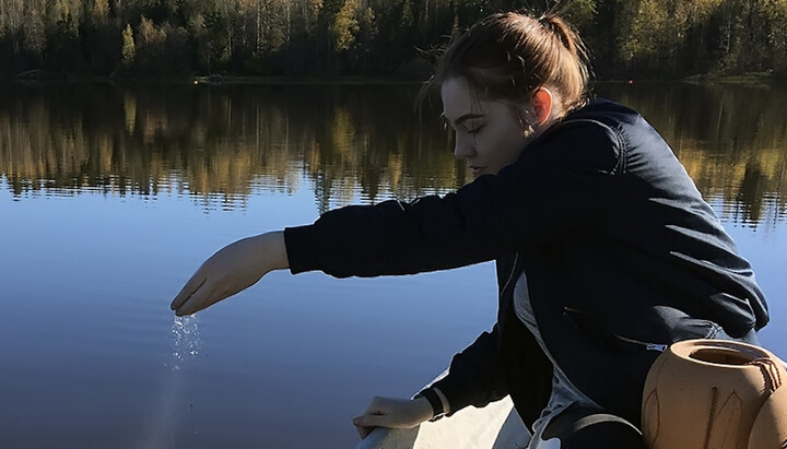Дівчина кидає прах покійного у воду. Фото: apostol54.ru