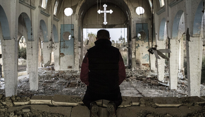 Христианин в Сирии молится в разрушенном храме. Фото: inosmi.ru