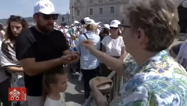 Женщина раздает католическое причастие желающим. Фото: YouTube-канал Vatican News